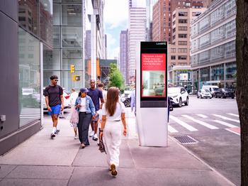 Pedestrians walking past a LinkNYC digital out-of-home advertising display in Midtown Manhattan, New York City.