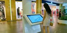 A woman looking at an interactive wayfinding screen in a mall. This type of screen is ideal for advertising.
