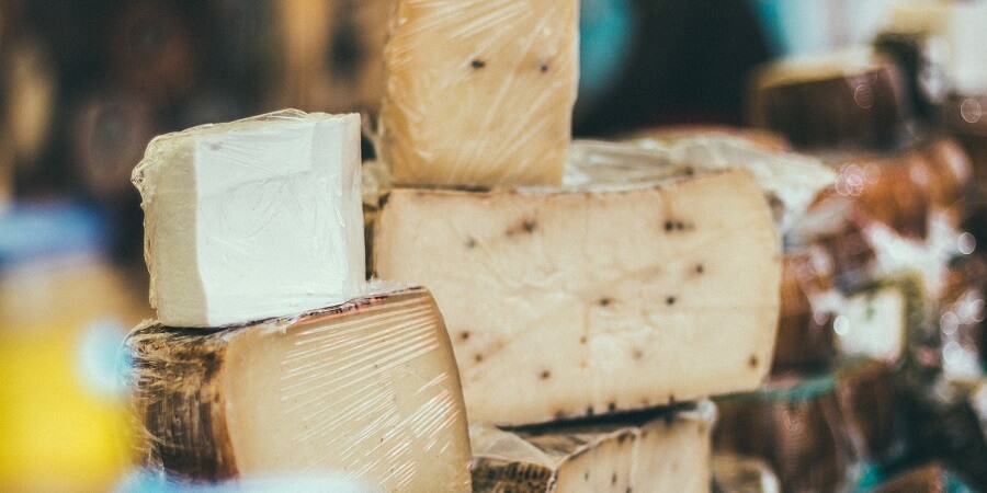 A stack of different cheeses, all in plastic wrap.